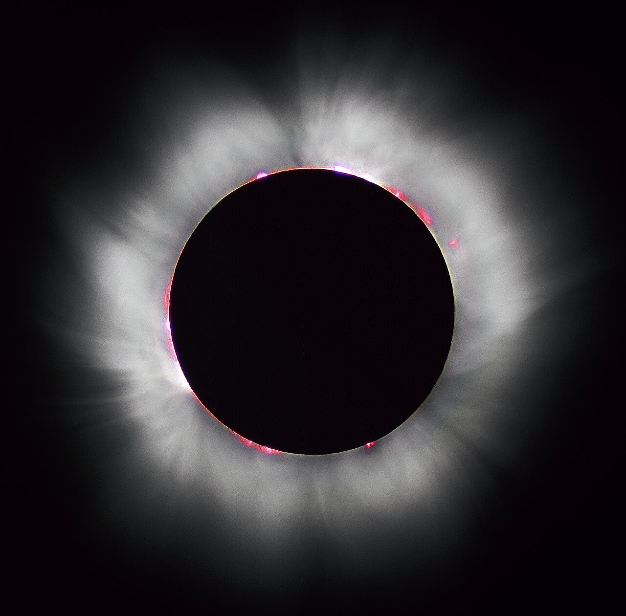Everything this site computes is the geometry behind this photograph, and the hardest parts of it are at the edges. The pink prominences ring a limb that is not a circle: lunar topography moves a path limit by 1 to 3 km, and the solar radius that sets where the corona begins is still disputed at a third of an arcsecond. Totality of 1999 August 11, photographed from France by Luc Viatour / lucnix.be, CC BY-SA 3.0 1 2.